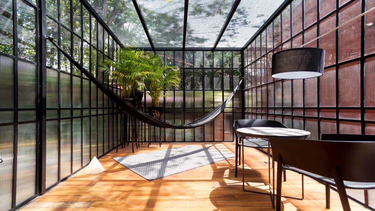 Een veranda in industriële stijl met zwarte meubels, hangmat en kamerplant.