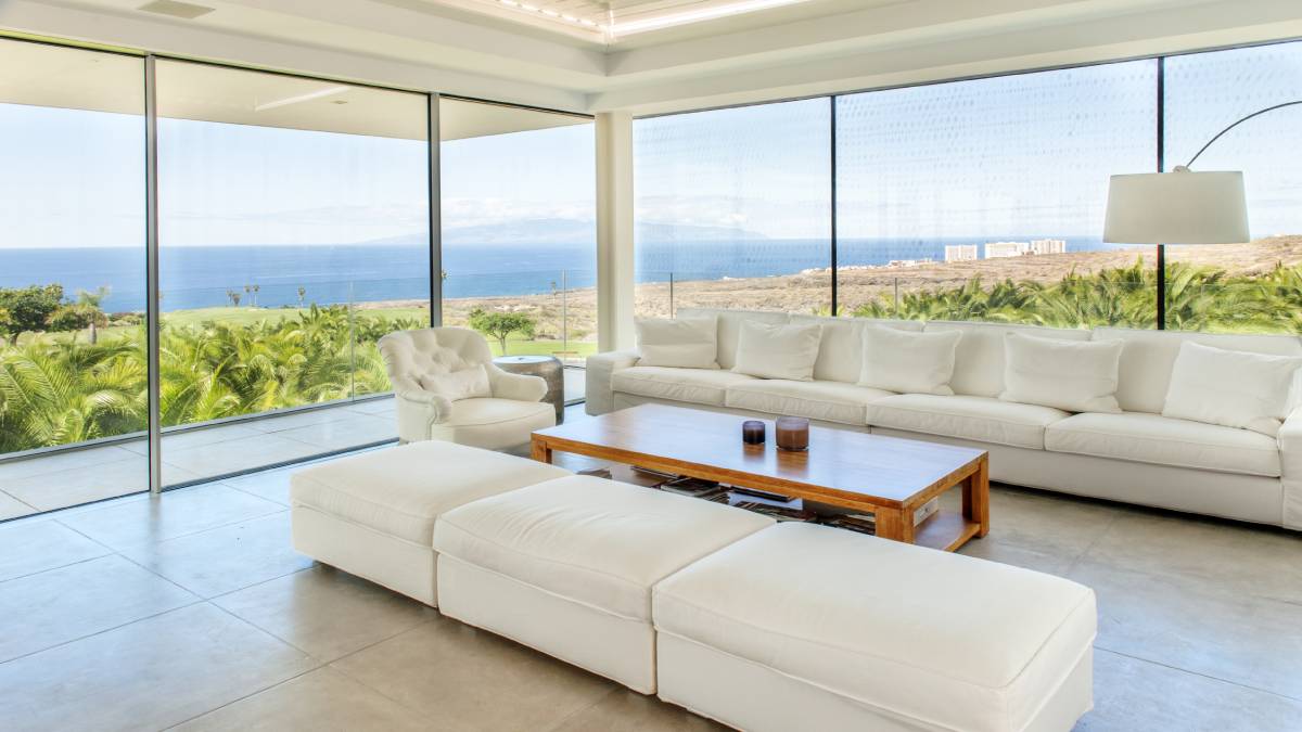Een moderne veranda met grote ramen en witte zetels, een stijlvol project aan een gemiddelde tot hoge prijs.