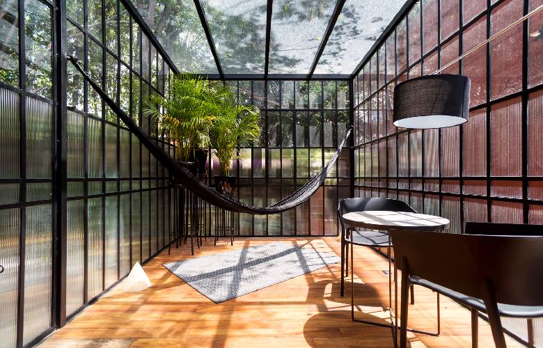 Een veranda in industriële stijl met zwarte meubels, hangmat en kamerplant.
