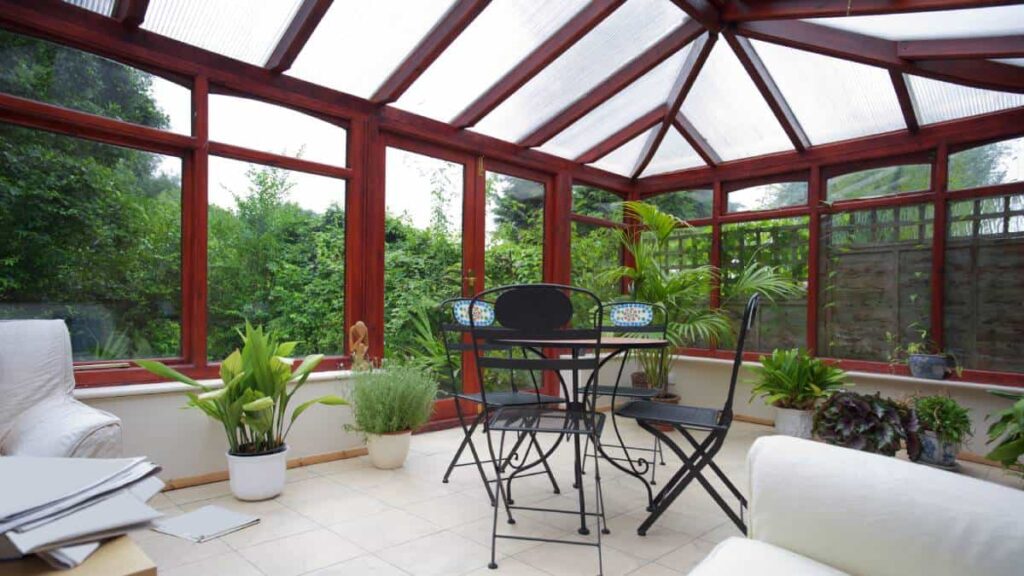 Een rode veranda van PVC met veel planten.